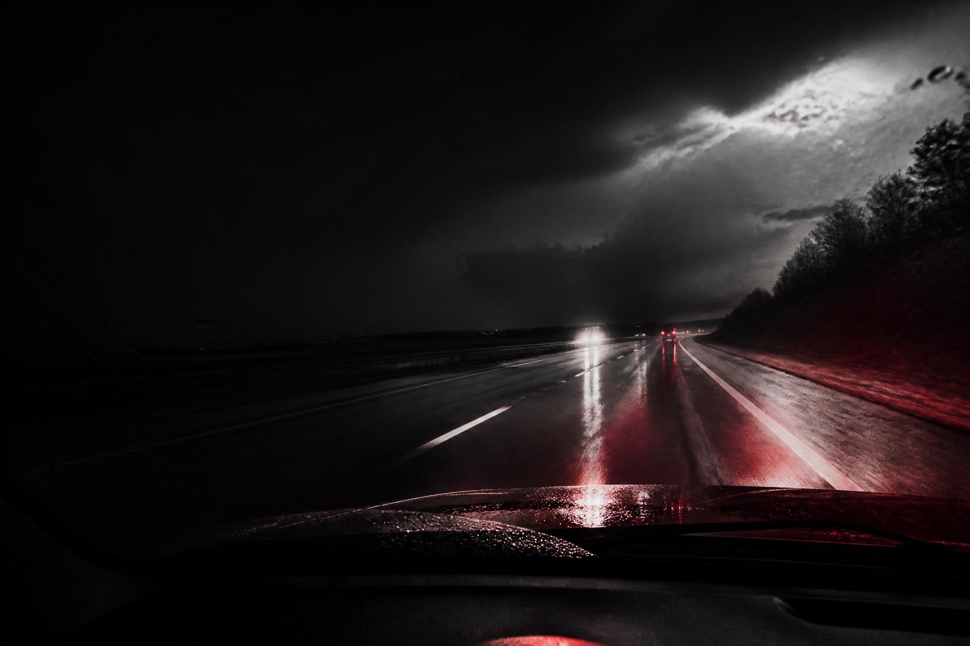 An empty highway seen through a rain-streaked windshield at night